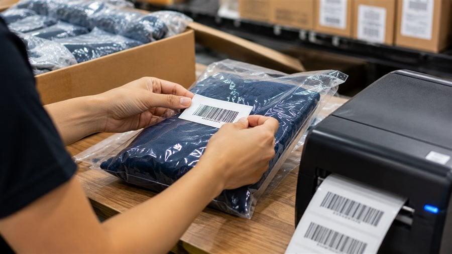 Close-up of an FNSKU barcode label being applied to a product at an FBA prep station